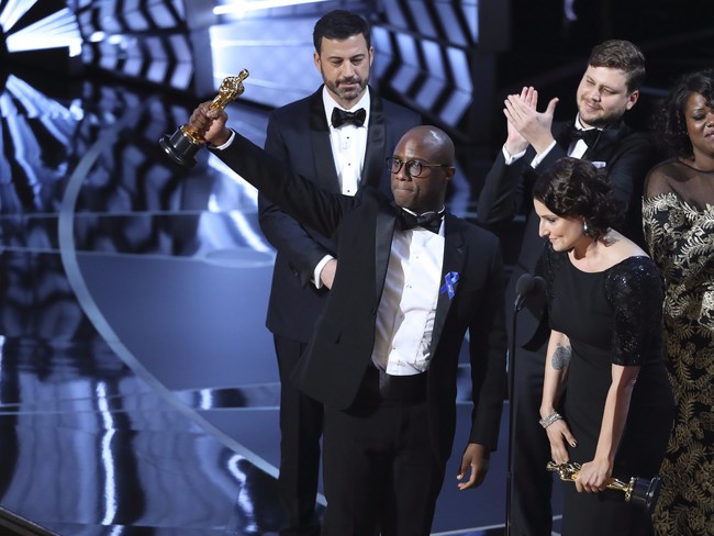 Jimmy Kimmel mira a Barry Jenkins alzando el Oscar